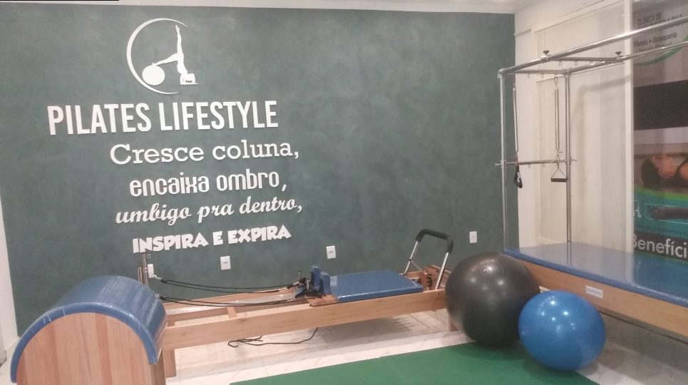 Aparelho reformer de Pilates em madeira, com bolas suíças ao lado